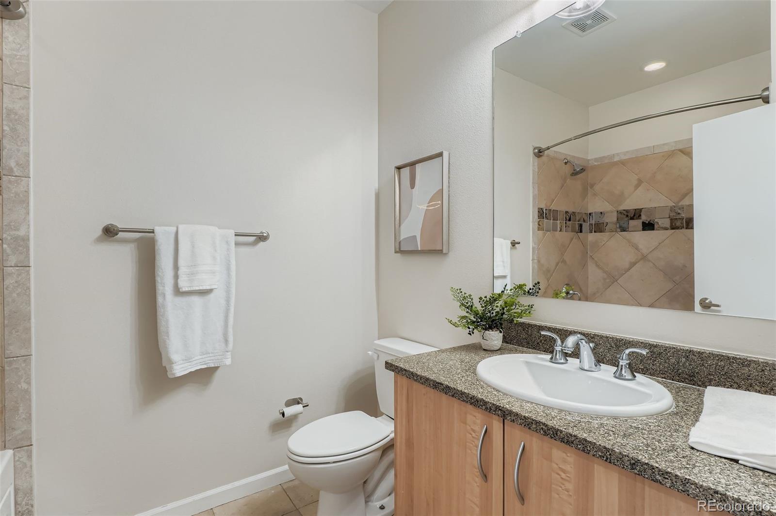 2680 Blake Street, Unit 18 Denver, CO 80205 - Photo 17 of 29 a bathroom with a granite countertop sink a toilet and a mirror
