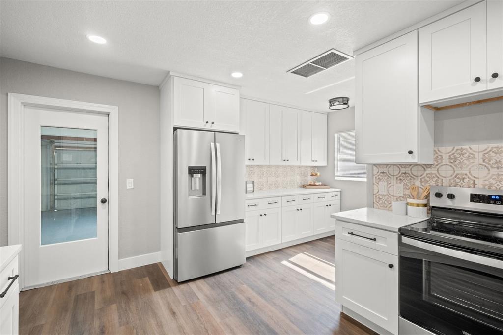1472 Ruth Road Dunedin, FL 34698 - Photo 14 of 50 a kitchen with a refrigerator stove and white cabinets