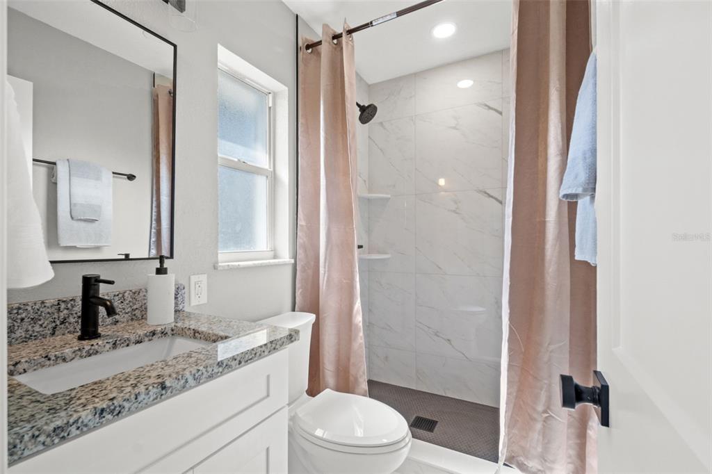 1472 Ruth Road Dunedin, FL 34698 - Photo 31 of 50 a bathroom with a granite countertop sink toilet mirror and shower