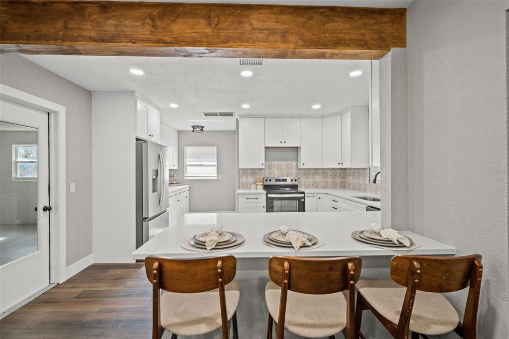 1472 Ruth Road Dunedin, FL 34698 - Photo 8 of 50 a kitchen with stainless steel appliances kitchen island granite countertop a dining table and chairs