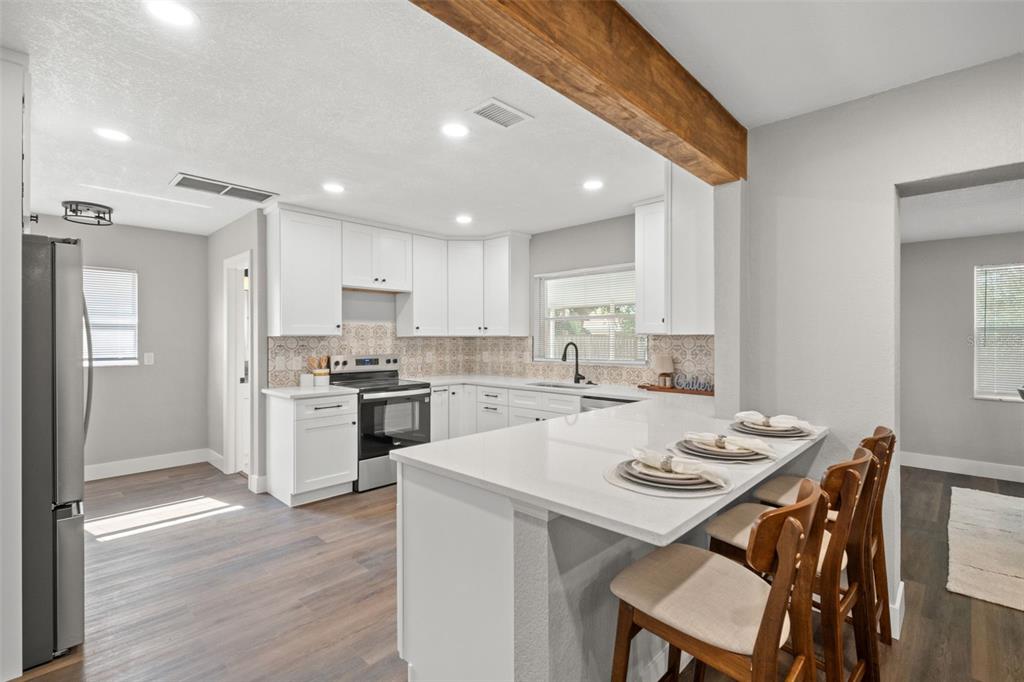 1472 Ruth Road Dunedin, FL 34698 - Photo 9 of 50 a kitchen with a sink a stove a refrigerator and white cabinets with wooden floor