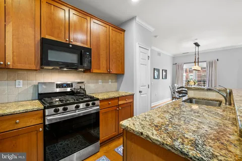 a kitchen with stainless steel appliances granite countertop a stove a sink and a microwave