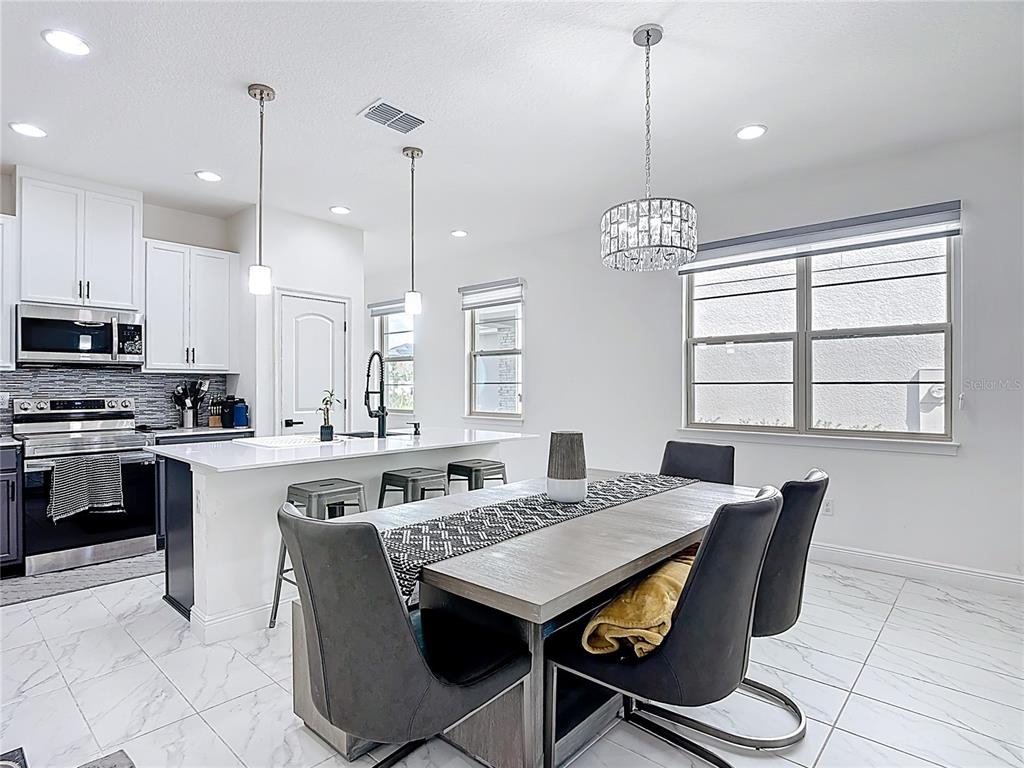 7541 Wing Span Way Harmony, FL 34773 - Photo 13 of 49 a kitchen with stainless steel appliances granite countertop a stove a kitchen island a stove a table and chairs