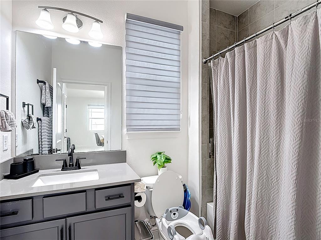 7541 Wing Span Way Harmony, FL 34773 - Photo 25 of 49 a bathroom with a sink a mirror and a shower curtain