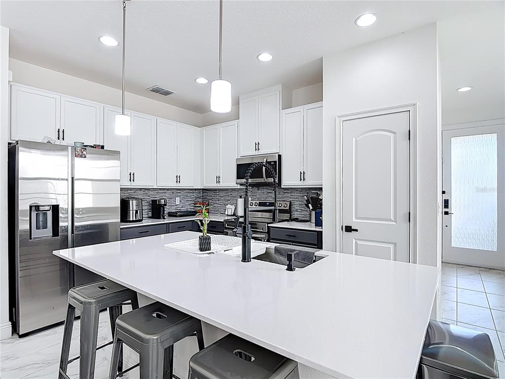 7541 Wing Span Way Harmony, FL 34773 - Photo 8 of 49 a kitchen with stainless steel appliances a table chairs refrigerator and microwave