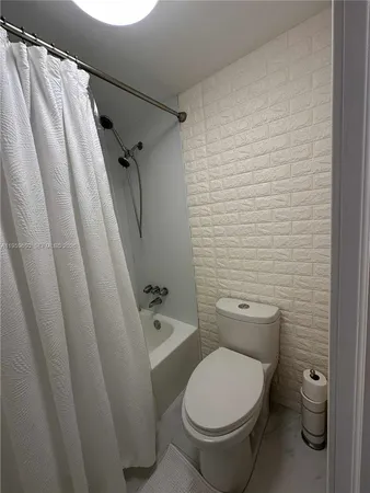 a white toilet sitting next to a shower curtain