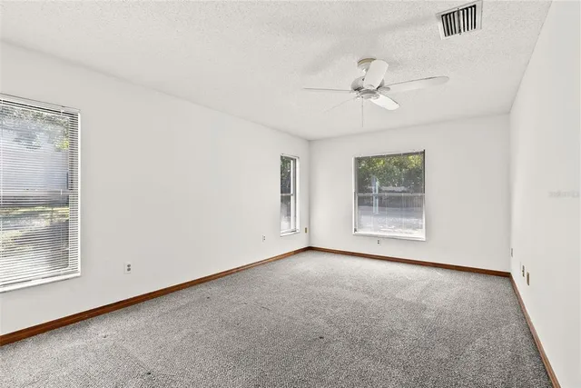 an empty room with windows and fan