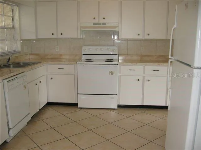 a kitchen with white cabinets and white appliances