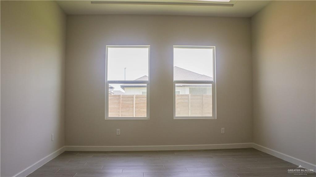 900 Azalea Street Mission, TX 78573 - Photo 9 of 12 Bright interior space featuring two windows, neutral painted walls, white baseboards, and wood-finish tile flooring