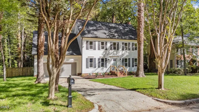 a front view of a house with garden and trees