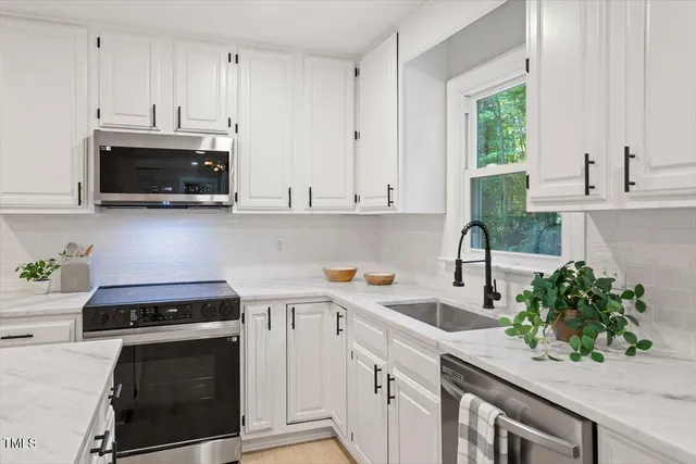 a kitchen with stainless steel appliances white cabinets and a stove top oven