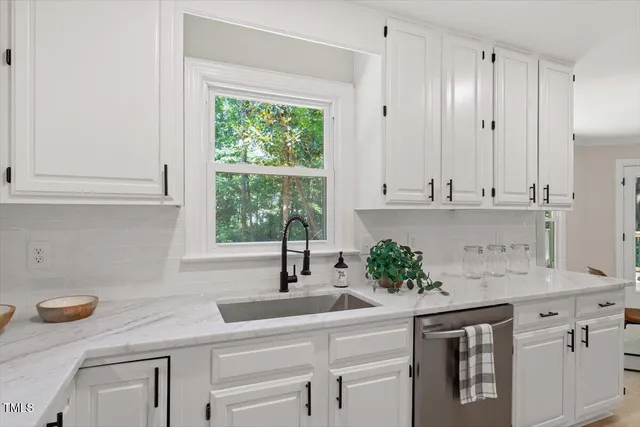 a kitchen with stainless steel appliances white cabinets and window