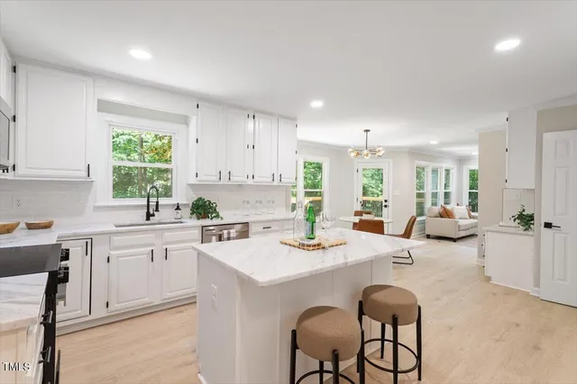 a kitchen with stainless steel appliances kitchen island granite countertop a stove a sink a dining table and chairs