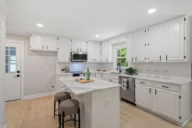 a kitchen with stainless steel appliances granite countertop a sink a stove a refrigerator and cabinets