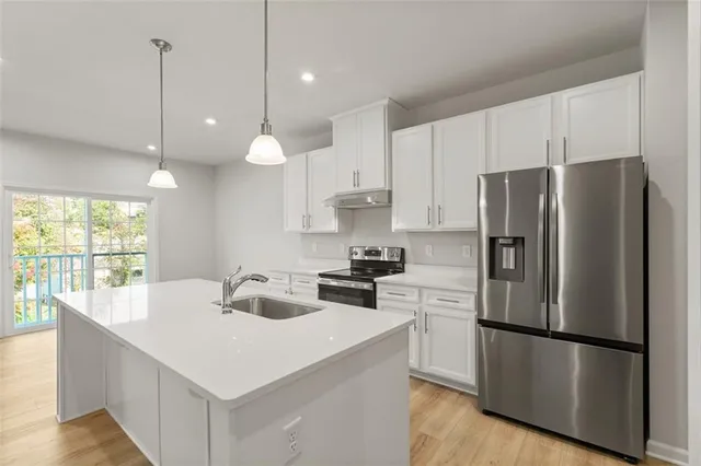 a kitchen that has a refrigerator a stove a sink and a center island