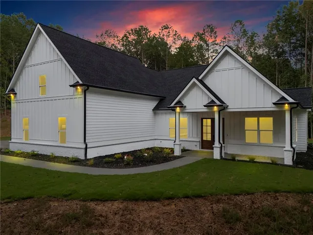 a view of a white house next to a yard and large trees