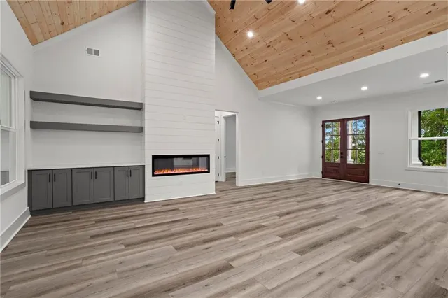 a view of an empty room with wooden floor and windows