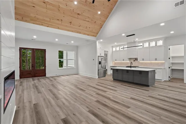a large white kitchen with kitchen island a sink stainless steel appliances and cabinets
