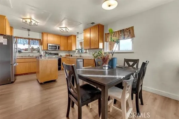 a dining area with stainless steel appliances kitchen island granite countertop a sink a stove a dining table and chairs