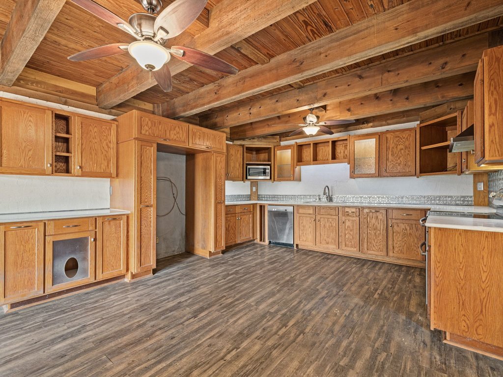 Rich wood plank flooring pairs with heavy beamed ceilings in this rustic kitchen space.