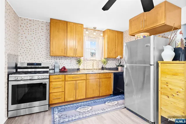 a kitchen with stainless steel appliances granite countertop a refrigerator a stove and a sink with wooden floor