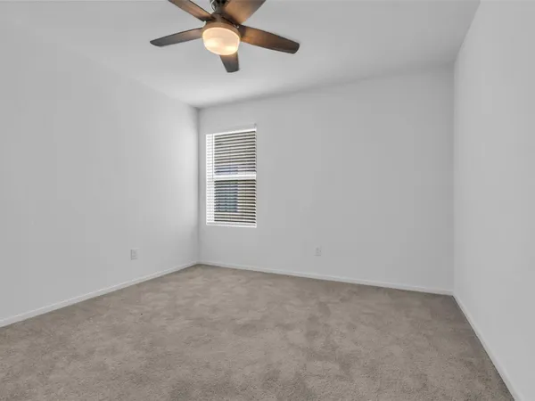 an empty room with a window and a fan