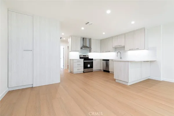 a view of kitchen with kitchen island a sink wooden floor and a refrigerator