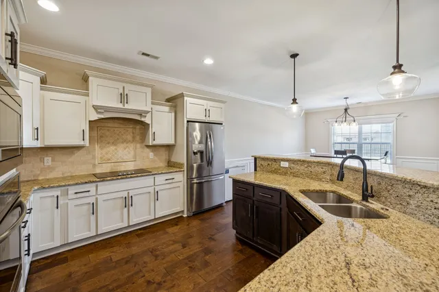 a large kitchen with stainless steel appliances granite countertop a sink a stove and a refrigerator