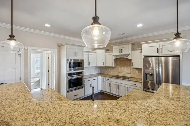 a kitchen with stainless steel appliances granite countertop a refrigerator and a stove top oven
