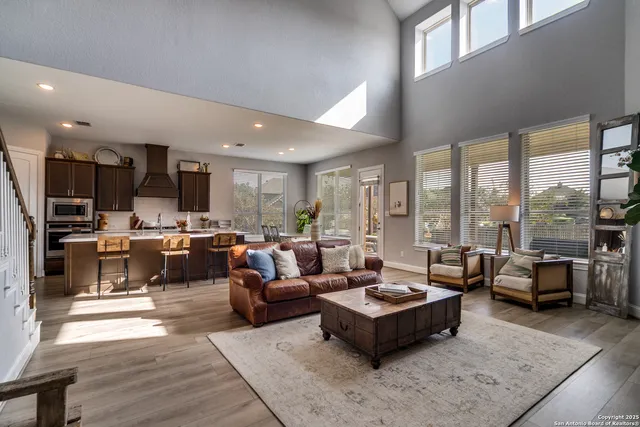 a living room with furniture kitchen area and a large window