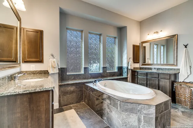 a bathroom with a granite countertop tub and a sink