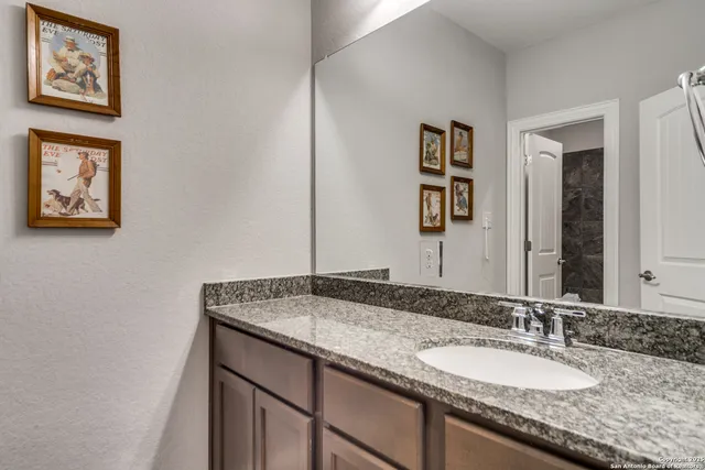 a bathroom with a granite countertop sink and a mirror