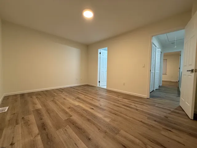 an empty room with wooden floor and bathroom view