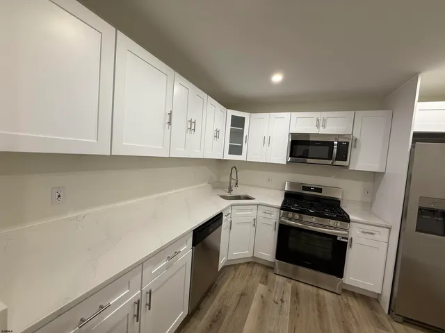 a kitchen with granite countertop white cabinets stainless steel appliances and sink