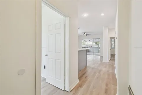 a view of a hallway with wooden floor cabinets and a bathroom