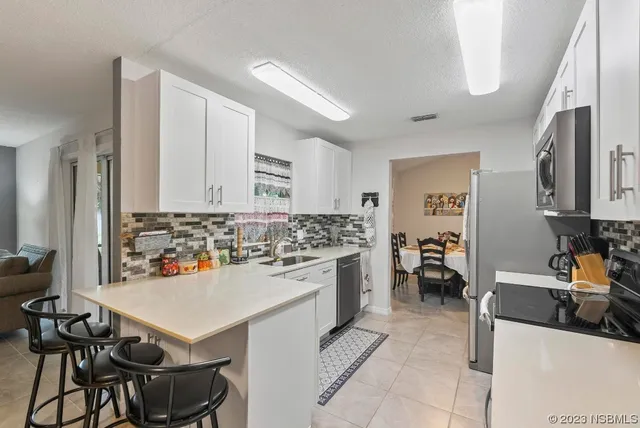 a kitchen with stainless steel appliances a stove a sink a refrigerator a microwave a refrigerator cabinets and wooden floor