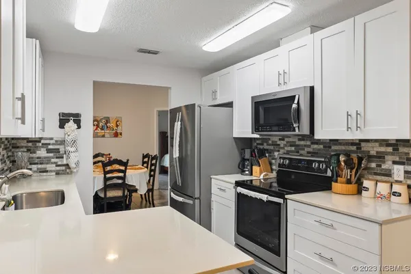 a white kitchen with a sink and a stove top oven