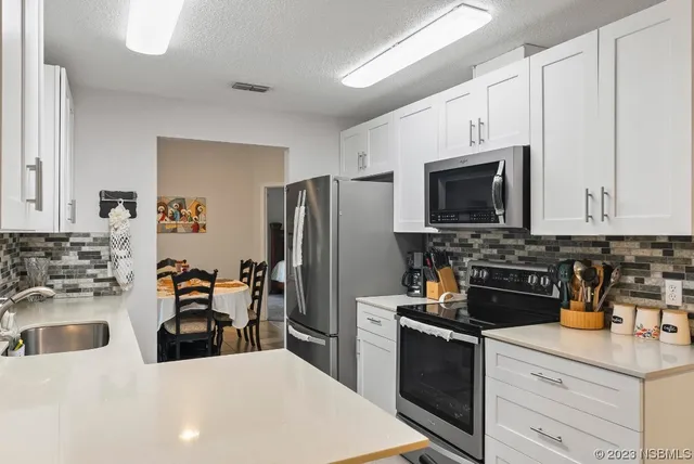 a white kitchen with a sink and a stove top oven