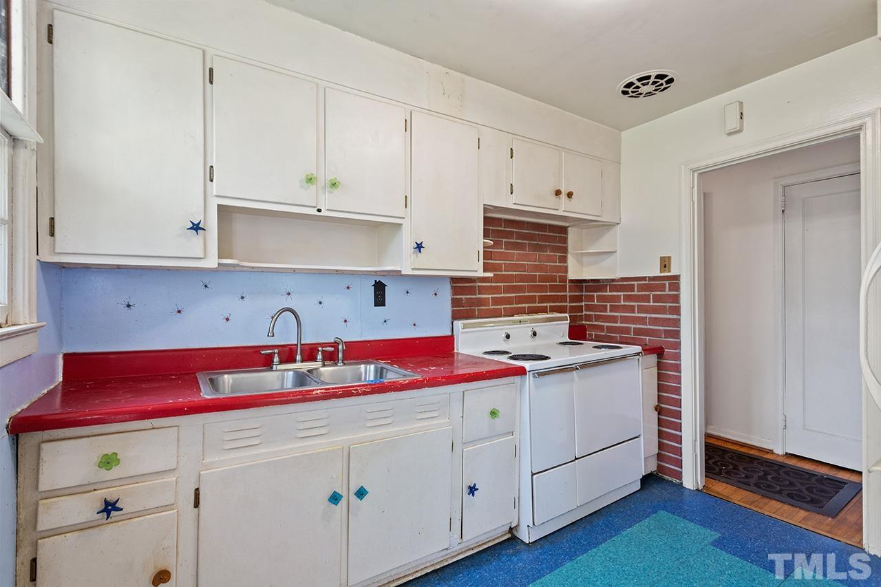 1208 Clifton Street Raleigh, NC 27604 - Photo 17 of 33 a kitchen with stainless steel appliances white cabinets sink and wooden floor