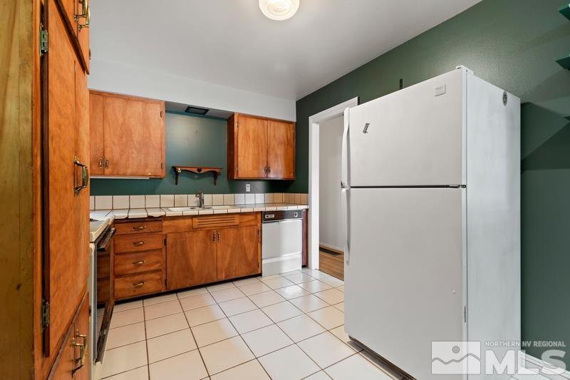 2490 Riviera Street Reno, NV 89509 - Photo 7 of 18 a kitchen with granite countertop a refrigerator a sink and white cabinets