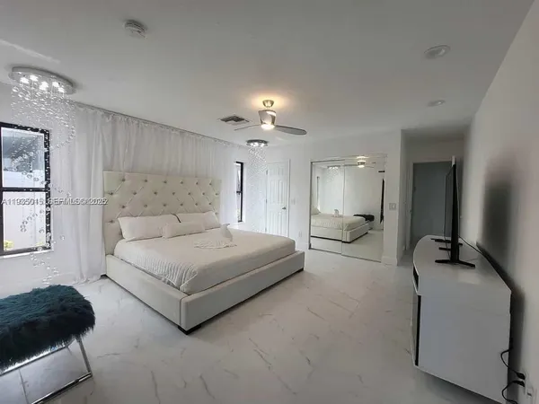 a spacious bedroom with a bed a couch and a chandelier