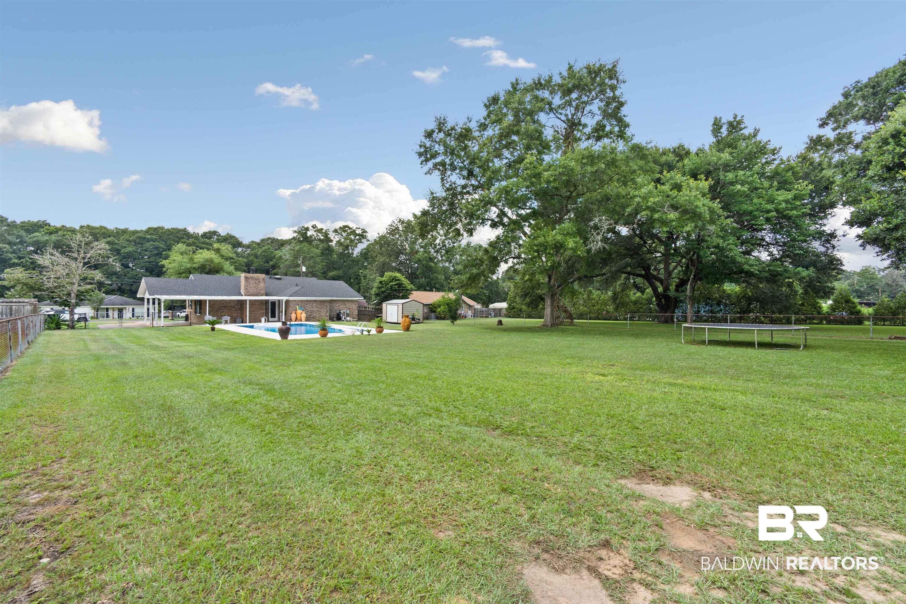 2000 Campfire Drive Semmes, AL 36575 - Photo 25 of 26 View of yard featuring a storage unit, a trampoline, and a fenced in pool