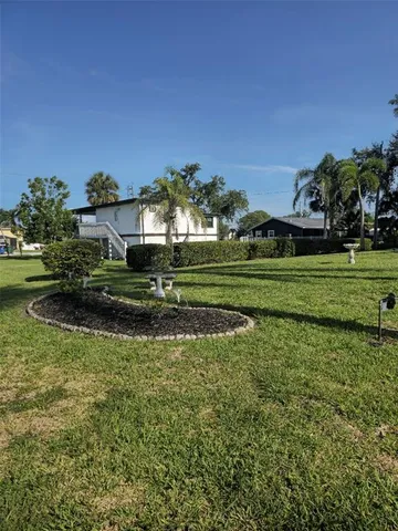 a view of a big house with a big yard and potted plants and large trees