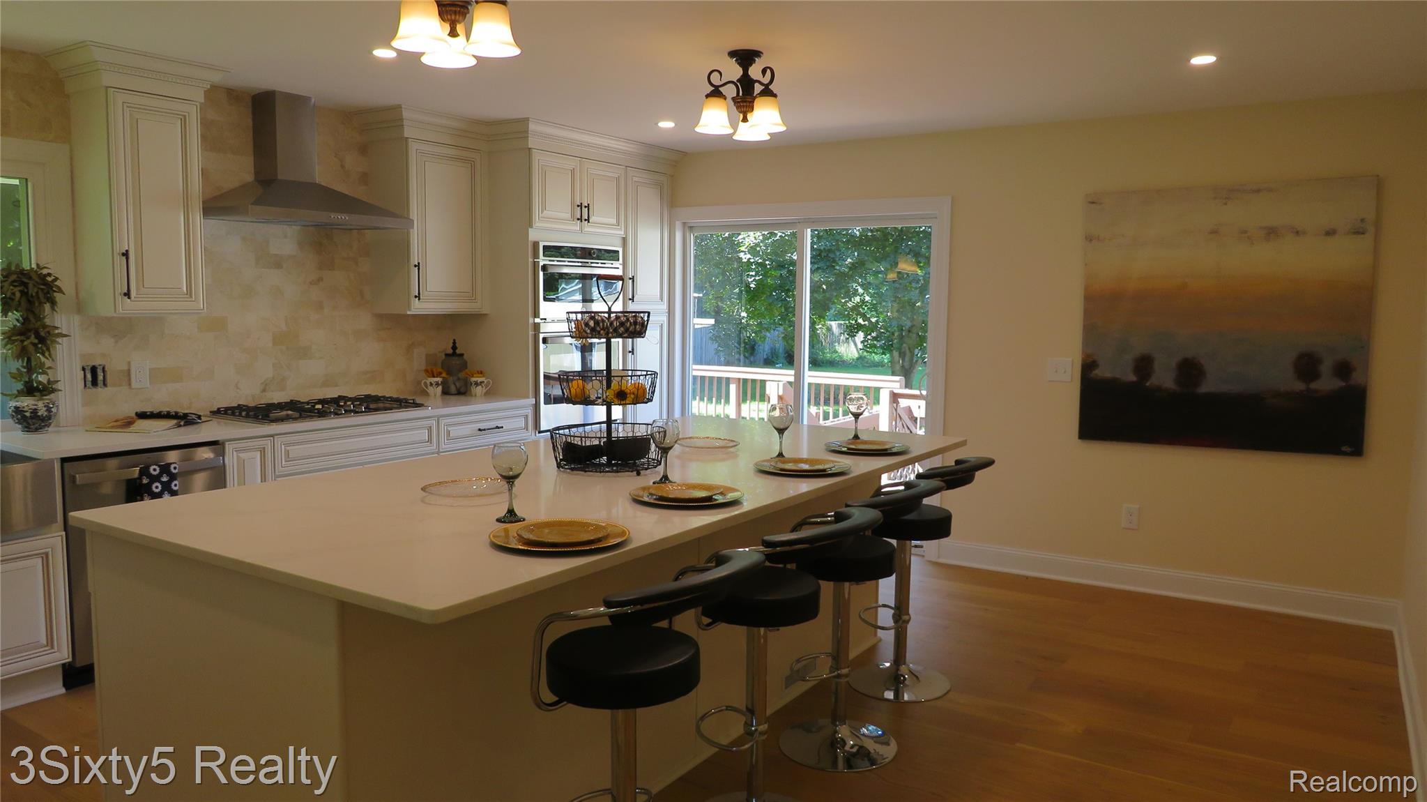 16558 Haggerty Road Belleville, MI 48111 - Photo 11 of 40 Bright kitchen featuring a substantial island with seating, stainless steel appliances, a gas cooktop, double wall ovens, and wood-finish flooring