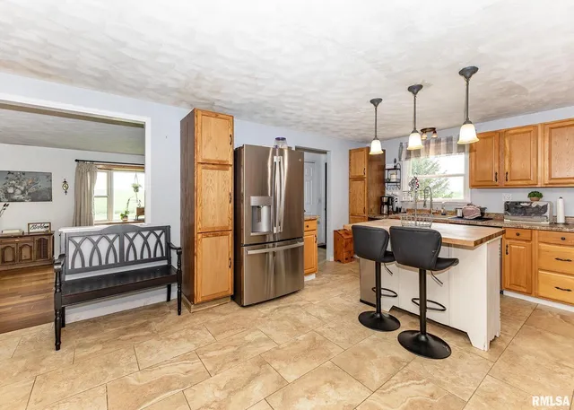 a kitchen with a stove a sink a microwave a dining table and chairs with wooden floor