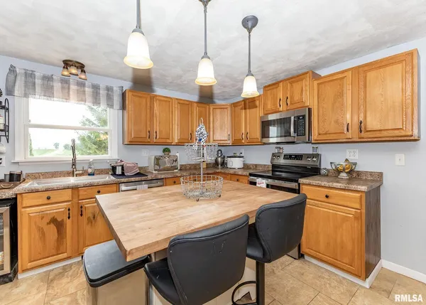 a kitchen with a stove a sink a microwave a dining table and chairs with wooden floor