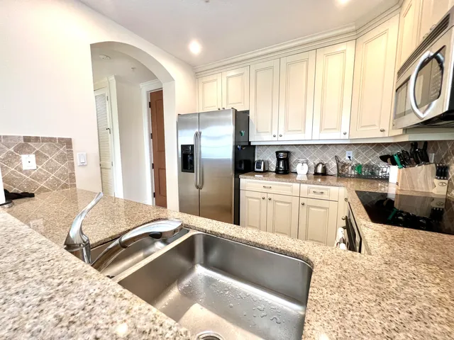 a kitchen with granite countertop a refrigerator sink and cabinets