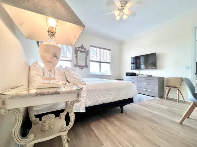 a bedroom with a bed a chandelier and a mirror on the dresser