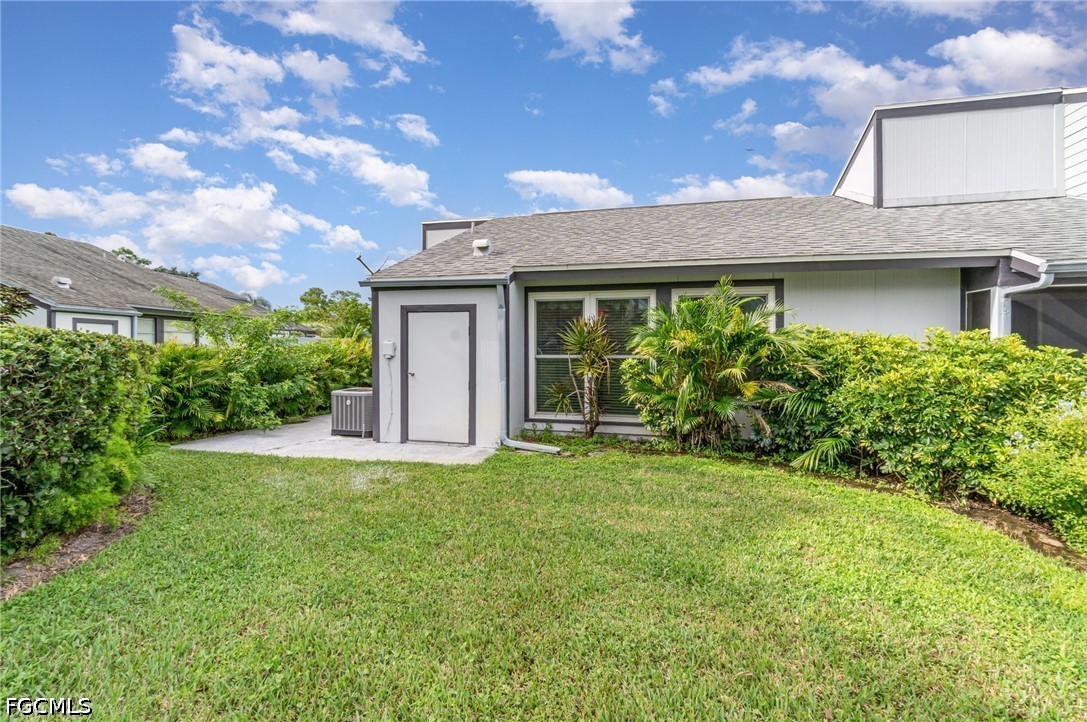10615 Roxbury Court Lehigh Acres, FL 33936 - Photo 25 of 33 a view of a house with brick walls and a yard with plants