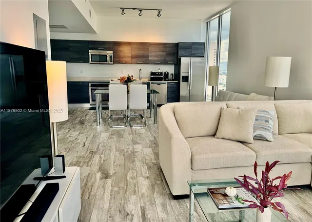 a living room with stainless steel appliances furniture a kitchen view and a fireplace